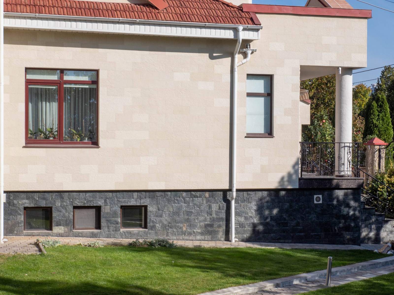 Façade latérale avec fenêtres, balcon à garde-corps en fer forgé et pierre flexible beige